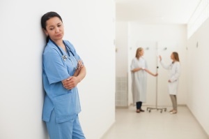 Nurse feeling sad with doctor talking to patient in hospital corridor
