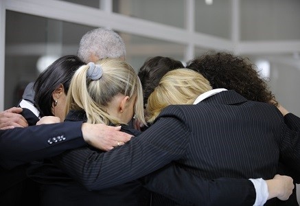 Team building event: businessmen in 'group hug' in office