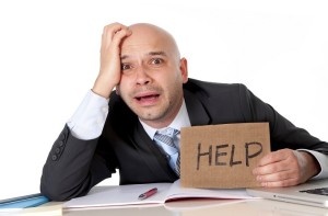 bald latin business man over worked holding a help sign